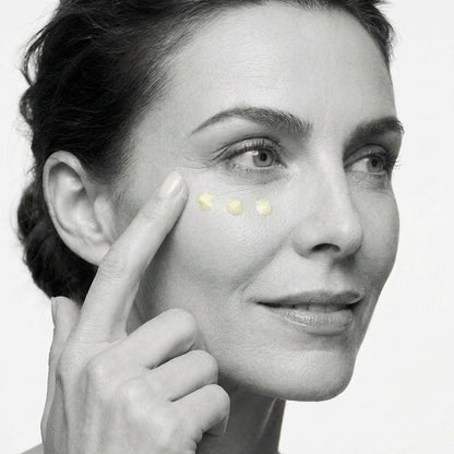 Woman applying cream to her face with a close-up of her eye area.