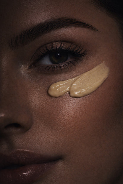 Close-up of a woman's face with two beige makeup swatches on her cheek.