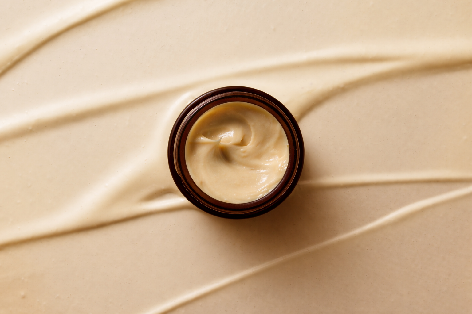 Jar of cream on a beige background with swirled cream